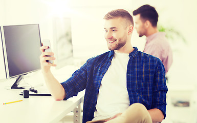 Image showing happy creative man texting on cellphone at office