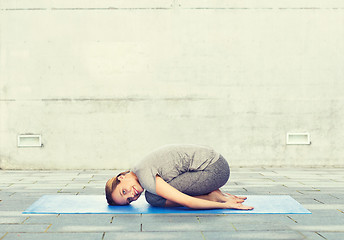 Image showing happy woman making yoga in child pose on mat