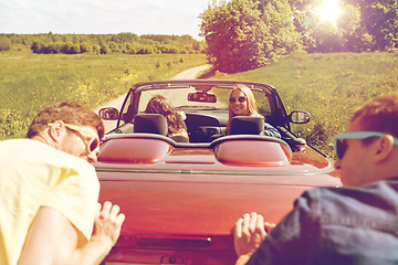 Image showing happy friends pushing broken cabriolet car