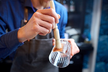 Image showing close up of bartender with glass and brush at bar