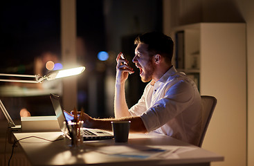 Image showing angry businessman with smartphone at night office