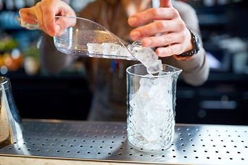 Image showing bartender pouring ice into glass jug at bar