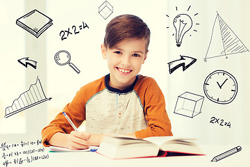 Image showing smiling student boy writing to notebook at home