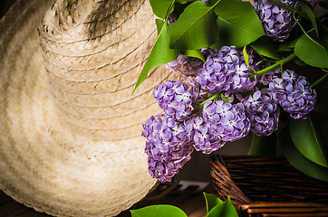 Image showing Still-life with a bouquet of lilacs and a straw hat, close-up