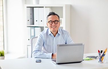 Image showing happy businessman in eyeglasses with laptop office