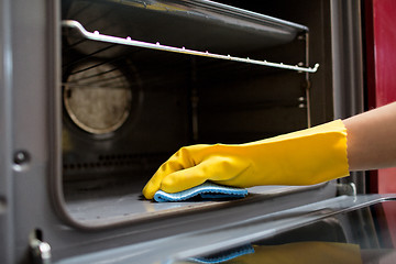 Image showing hand with rag cleaning oven at home kitchen