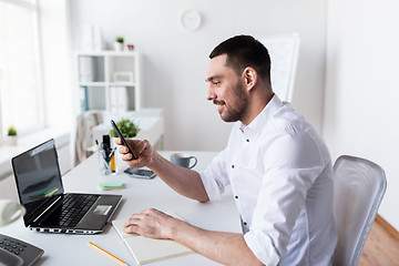 Image showing businessman with smartphone and notebook at office