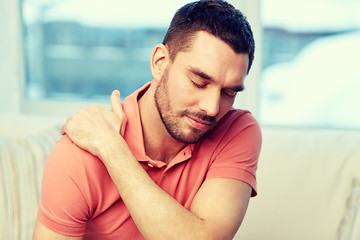 Image showing unhappy man suffering from neck pain at home