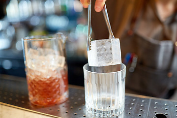 Image showing bartender adding ice cube into glass at bar