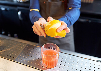 Image showing bartender removing peel from lime at bar