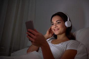 Image showing woman with smartphone and headphones in bed