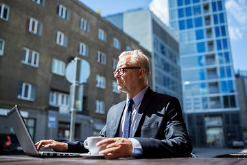 Image showing senior businessman with laptop drinking coffee