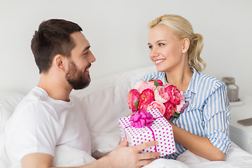 Image showing happy couple with gift box in bed at home