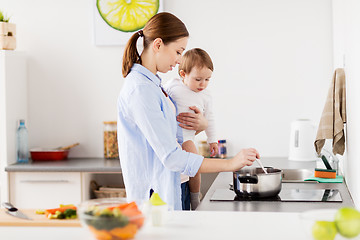 Image showing happy mother and baby cooking at home kitchen