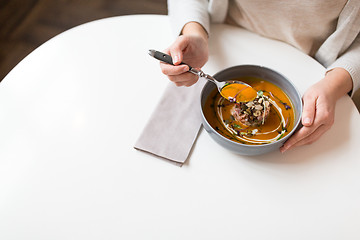 Image showing woman eating pumpkin cream soup at restaurant