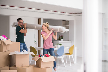 Image showing couple carrying a carpet moving in to new home