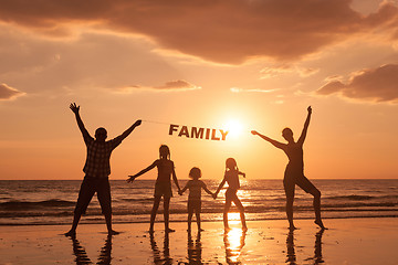 Image showing Happy family standing on the beach at the sunset time.