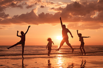 Image showing Father and children playing on the beach at the sunset time. 