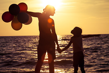 Image showing Mother and daughter playing on the beach at the sunset time. 