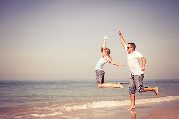 Image showing Father and daughter playing on the beach at the day time.