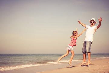 Image showing Father and daughter playing on the beach at the day time. 