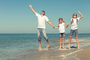 Image showing Father and daughters playing on the beach at the day time.