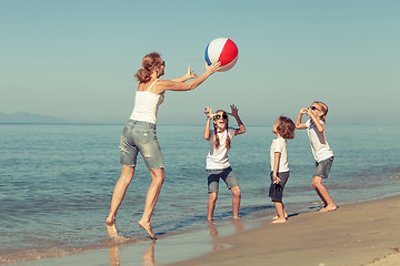 Image showing Mother and  children playing on the beach.