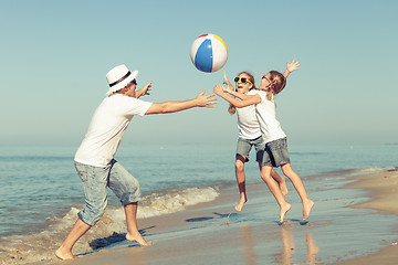 Image showing Father and daughters playing on the beach at the day time.