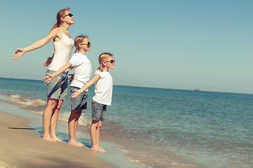 Image showing Mother and daughters  playing on the beach at the day time.