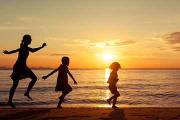 Image showing Mother and children standing on the beach at the sunset time.