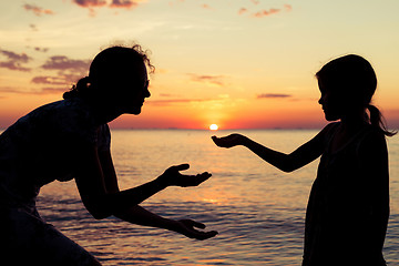 Image showing Mother and daughter playing on the beach at the sunset time.