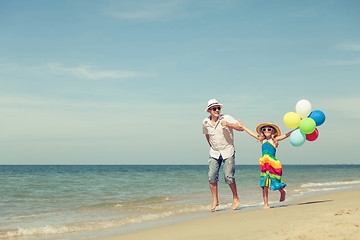 Image showing Father and daughter with balloons playing on the beach at the da