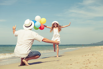 Image showing Father and daughter with balloons playing on the beach at the da