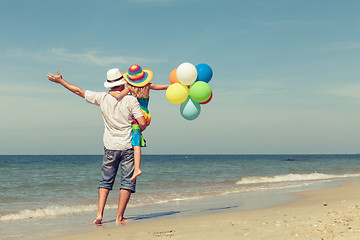 Image showing Father and daughter with balloons playing on the beach at the da