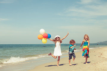 Image showing Three happy children dancing on the beach at the day time