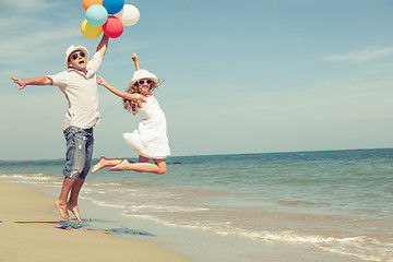 Image showing Father and daughter with balloons playing on the beach at the da