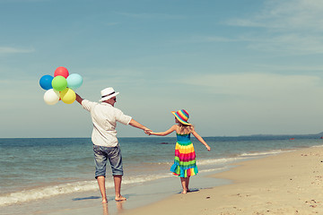 Image showing Father and daughter with balloons playing on the beach at the da