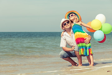 Image showing Father and daughter with balloons playing on the beach at the da