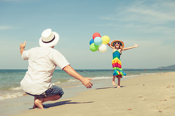 Image showing Father and daughter with balloons playing on the beach at the da