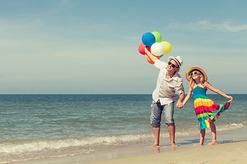 Image showing Father and daughter with balloons playing on the beach at the da