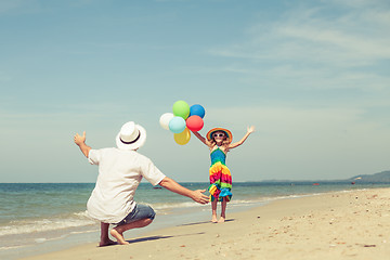 Image showing Father and daughter with balloons playing on the beach at the da