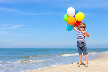 Image showing Little boy with balloons standing on the beach