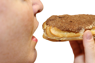 Image showing Close up of a young woman eating a cake eclair over white background.