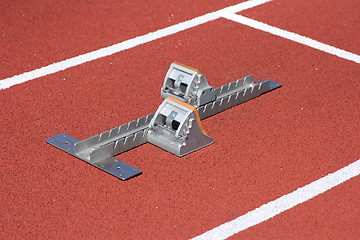 Image showing Athletics starting blocks on race red track