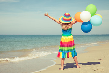 Image showing Little girl with balloons standing on the beach