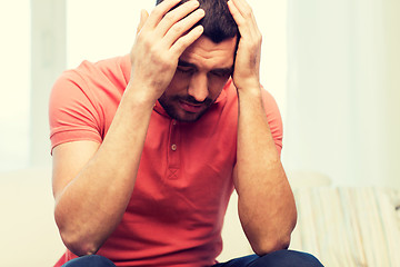 Image showing unhappy man suffering from head ache at home