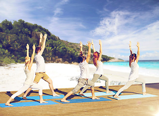 Image showing group of people making yoga exercises on beach