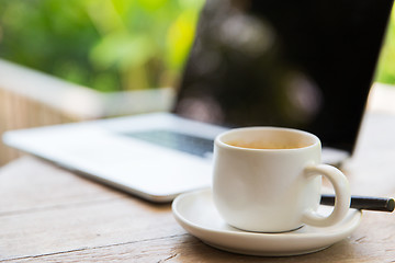 Image showing close up of coffee cup and laptop on table