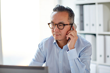 Image showing businessman with laptop calling on smartphone