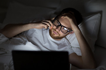 Image showing man with laptop calling on smartphone at night